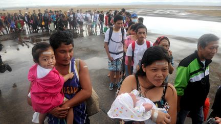 Des survivants du typhon Haiyan embarquent &agrave; bord d'un avion militaire C 130 &agrave; l'a&eacute;roport de Tacloban (Philippines) pour quitter la ville d&eacute;vast&eacute;e, le 13 novembre 2013. (NOEL CELIS / AFP)