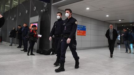 Des policiers patrouillent à l'aéroport Roissy-Charles-de-Gaulle, un masque sur le visage pour se protéger du coronavirus (illustration, 26 janvier 2020). (ALAIN JOCARD / AFP)