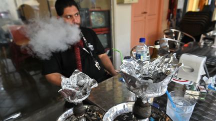 Un homme fume le narguil&eacute; dans un bar &agrave; chicha de Singapour, le 4 novembre 2014. (ROSLAN RAHMAN / AFP)