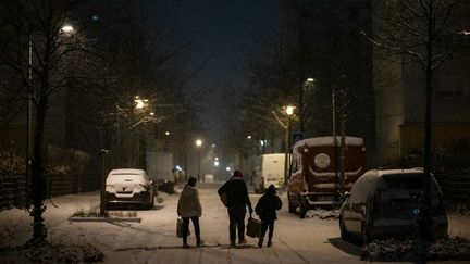 Des piétons marchent dans une rue recouverte de neige après avoir reçu de la nourriture distribuée par un bénévole de l'association française "L'Ordre de Malte", à Colmar (Haut-Rhin), le 9 janvier 2024. (SEBASTIEN BOZON / AFP)