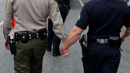 Deux membres des forces de l'ordre se tiennent la main pendant la Gay Pride à Hollywood (Californie), le 12 juin 2016. (MARK RALSTON / AFP)