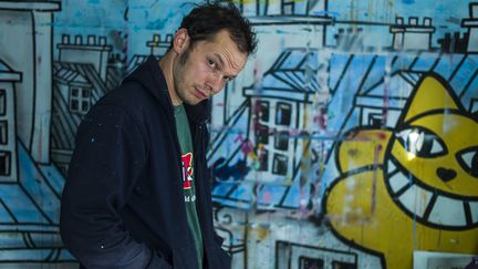 L'artiste Thoma Vuille, connu sous le nom de M. Chat, pose devant l'une de ses oeuvres à Paris, le 17 septembre 2014. (FRED DUFOUR / AFP)