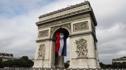 L'Arc de Triomphe décoré d'un drapeau français, le 14 juillet 2019 à Paris. (LUDOVIC MARIN / AFP)