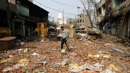 Un homme marche sur des débris dans une zone touchée par des violences intercommunautaires à New Delhi (Inde), le 26 février 2020.&nbsp; (ADNAN ABIDI / REUTERS)