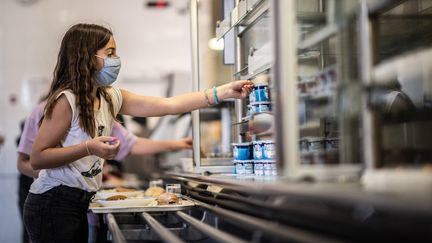 Une élève se sert dans une cafétéria d'un collège à&nbsp;Vincennes, le 1er septembre 2020 (photo d'illustration). (MARTIN BUREAU / AFP)