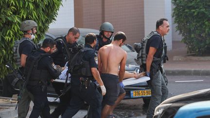 Des soldats israéliens secourent un blessé après une attaque de roquettes depuis la bande de Gaza, le 7 octobre 2023 à Ashkelon (Israël). (AHMAD GHARABLI / AFP)