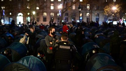 Des gendarmes debout au milieu des migrants et associations place de la République, le 23 novembre 2020, à Paris. (MARTIN BUREAU / AFP)