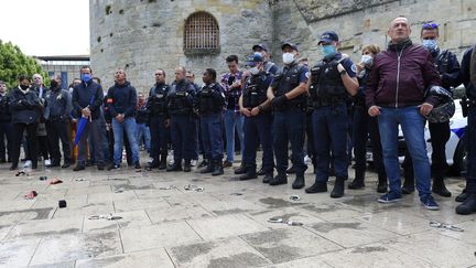 Des policiers manifestent, devant leurs menottes posées à terre, le 12 juin 2020 à Bordeaux (Gironde). (NICOLAS TUCAT / AFP)