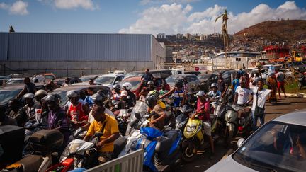 Bidons à la main, des dizaines de Mahorais jouaient des coudes devant la station-service du quartier de Kawéni, plus grand bidonville de France, le 20 décembre 2024. Tous ont l'espoir de repartir avec un peu de carburant, notamment pour faire tourner les groupes électrogènes, malgré l'interdiction des autorités de remplir bidons et jerricans. (DIMITAR DILKOFF / AFP)