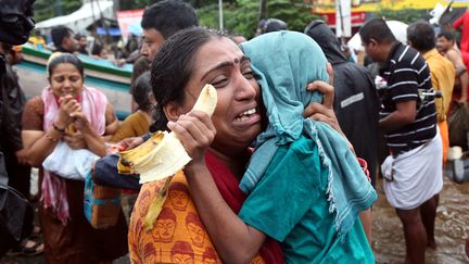 Une femme agrippe son fils et pleure après qu'ils ont été évacués d'une zone inondée à Aluva dans l'Etat du Kerala en Inde, le 18 août 2018.&nbsp; (SIVARAM V / REUTERS)