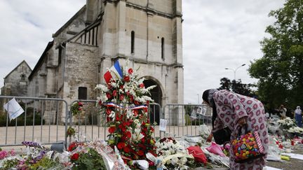 Une femme musulmane dépose des fleurs devant l'église Saint-Etienne de Saint-Etienne-du-Rouvray (Seine-Maritime), en hommage au prètre tué à l'arme blanche par des terroristes, vendredi 29 juillet. (CHARLY TRIBALLEAU / AFP)