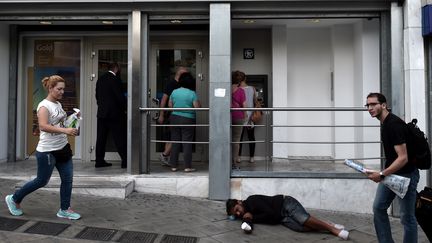 Des Grecs retirent de l'argent dans un distributeur d'Ath&egrave;nes, vendredi 19 juin. Les retraits dans le pays se sont acc&eacute;l&eacute;r&eacute;s en raison de la difficult&eacute; du gouvernement &agrave; obtenir un accord avec ses cr&eacute;anciers. (ARIS MESSINIS / AFP)