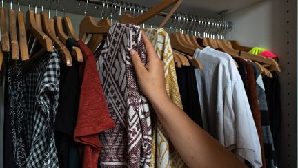 Une femme choisit dans sa garde-robe des vêtements à donner pour qu'ils soient recyclés. Versailles, septembre 2020 (KARINE P?RON LE OUAY / HANS LUCAS)