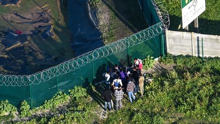 Un groupe de personnes devant les grillages de Calais (Pas-de-Calais), le 14 octobre 2017. (FRANCOIS LO PRESTI / AFP)