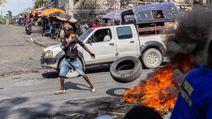 Un homme met le feu à un pneu dans les rues de Port-au-Prince, à Haïti, le 12 mars 2024. (GUERINAULT LOUIS / ANADOLU / AFP)