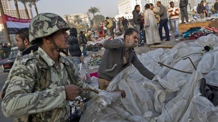 Un militaire et un civil en train de démonter une tente place Tahrir au Caire le 13 février 2010 (AFP - PEDRO UGARTE)