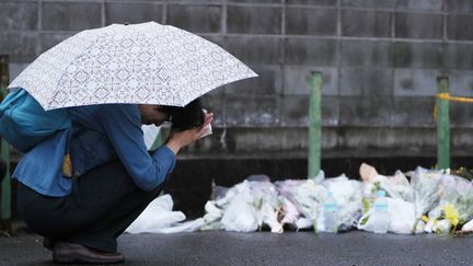 Une femme se recueille, le 19 juillet 2019, devant un autel pour les personnes disparues installé à proximité du studio d'animation incendié jeudi à Kyoto (Japon). (MAMI NAGAOKI / YOMIURI / AFP)