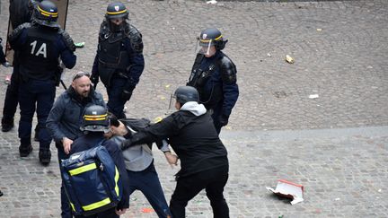 Alexandre Benalla (à droite), Vincent Crase (à gauche) et plusieurs policiers autour d'un jeune homme,&nbsp;le 1er-Mai à Paris. (NAGUIB-MICHEL SIDHOM / AFP)