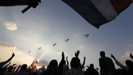 Des opposants au pr&eacute;sident Mohamed Morsi d&eacute;filent sur la place Tahrir, tandis que des h&eacute;licopt&egrave;res de l'arm&eacute;e suvolent le ciel du Caire (Egypte), lundi 1er juillet.&nbsp; (MOHAMED ABD EL GHANY / REUTERS)