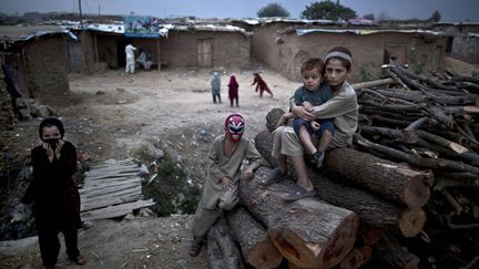 Une jeune r&eacute;fugi&eacute; afghan porte un masque dans un bidonville d'Islamabad (Pakistan), le 30 octobre 2013. (MUHAMMED MUHEISEN / AP / SIPA)