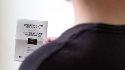 Un homme tient un certificat papier de vaccination pouvant servir de pass sanitaire en France. (MAUD DUPUY / HANS LUCAS / AFP)