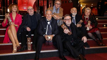 Marie-Anne Chazel, Michel Blanc, Christian Clavier, Thierry Lhermitte, Bruno Moynot, Gérard Jugnot et Josiane Balasko posent avec le trophée après avoir reçu le Prix anniversaire lors de la 46e édition de la cérémonie des César du cinéma à l'Olympia, à Paris, le 12 mars 2021. (THOMAS SAMSON / AFP)