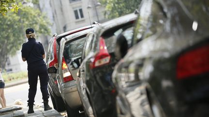 Un agent de surveillance de la ville de Paris verbalise une voiture le 17 juillet 2013. (MAXPPP)