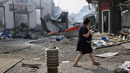 Une femme passe devant des boutiques détruites à&nbsp;Sloviansk (Ukraine), le 3 juillet 2022. (AFP)