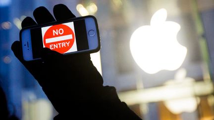 &nbsp; (Un homme tient un iPhone avec un signe "Sens interdit" à l'occasion d'une manifestation pour défendre la protection des données des utilisateurs d'Apple (New York) © Maxppp)