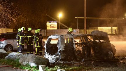 Des pompiers éteignent un feu de voiture après les émeutes à Grenoble (Isère), le 3 mars 2019. (JEAN-PIERRE CLATOT / AFP)