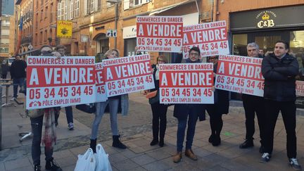 Des commerçants brandissent&nbsp;un panneau "à vendre" avec comme contact, le numéro de téléphone de la préfecture, le 16 janvier 2019. (ALAIN GASTAL / FRANCEINFO)