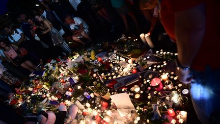 Un groupe se recueille, dépose des fleurs et allume des bougies sur la Promenade des Anglais à Nice.&nbsp; (GIUSEPPE CACACE / AFP)