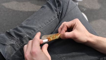 Un participant à la Marche mondiale du cannabis roule un joint, le 29 avril 2017 à Paris. (ALAIN JOCARD / AFP)