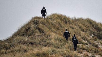 Des officiers de police patrouillent sur les dunes d'un plage de Wimereux, dans le Nord de la France, le 20 décembre 2021.&nbsp; (DENIS CHARLET / AFP)