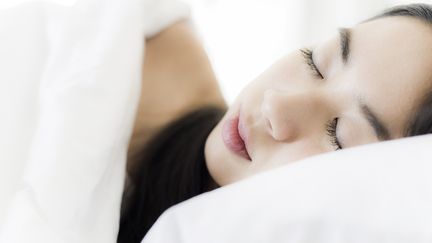 Une jeune femme dort la tête sur l'oreiller. (FREDERIC CIROU / MAXPPP)