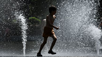 Un enfant se rafraichit dans une fontaine à Toulouse (Haute-Garonne), le 18 mai 2022. (VALENTINE CHAPUIS / AFP)