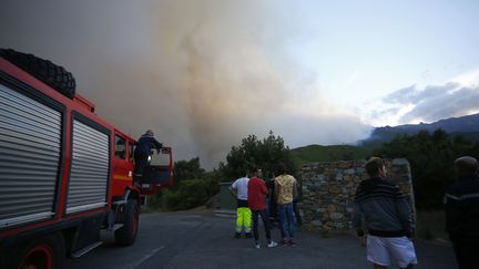 Des pompiers et des habitants observent l'incendie qui sévit à Pietracorbara (Corse), le 11 août 2017. (PASCAL POCHARD-CASABIANCA / AFP)