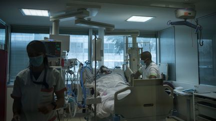 Des soignants au chevet d'un patient, malade du Covid-19, sous assistance respiratoire dans une unité de soins intensifs du centre hospitalier intercommunal André-Grégoire de Montreuil, le 14 décembre 2021. (JULIEN DE ROSA / AFP)