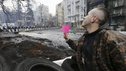 Un opposant pro-europ&eacute;en brandit un c&oelig;ur en direction des forces de l'ordre, le 14 f&eacute;vrier 2014 &agrave; Kiev (Ukraine).&nbsp; (REUTERS)