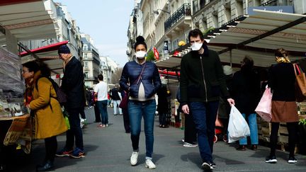 Un couple déambule dans les allées d'un marché à Montmartre (Paris), le 22 mars 2020. (EDOUARD RICHARD / HANS LUCAS)