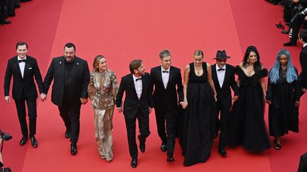 Quelques minutes avant le début de la cérémonie d'ouverture, le président du jury Ruben Östlund (au centre) et les membres du jury se sont tenu la main pour monter les marches. De gauche à droite : l'acteur américain Paul Dano, l'acteur français Denis Ménochet,  l'artiste Brie Larson, le président du jury, le réalisateur argentin Damián Szifrón, la réalisatrice française Julia Ducournau,  l'écrivain et réalisateur franco-afghan Atiq Rahimi, la réalisatrice Maryam Touzani et la réalisatrice, scénariste et actrice zambienne Rungano Nyoni. (ANTONIN THUILLIER / AFP)