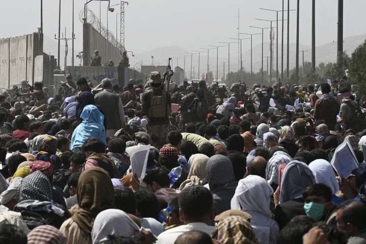 Des Afghans attendent face à l'une des portes de&nbsp;l'aéroport de Kaboul, le 20 août 2021. (WAKIL KOHSAR / AFP)