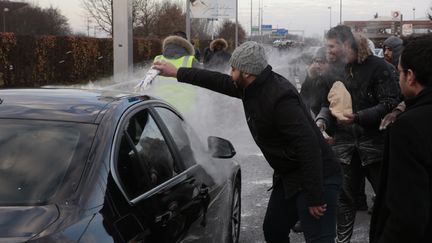 Des chauffeurs de VTC lancent de la farine sur un véhicule, près de l'aéroport Roissy&nbsp;Charles-de-Gaulle, le 16 décembre 2016. (GEOFFROY VAN DER HASSELT / AFP)