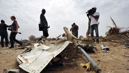 Des journalistes observent, samedi 26 juillet 2014, les d&eacute;bris du vol d'Air Alg&eacute;rie qui s'est &eacute;cras&eacute; au Mali, avec &agrave; son bord 118 personnes. (SIA KAMBOU / AFP)