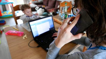 Une mère de famille télétravaille en gardant son enfant durant le confinement, le 16 mars 2020. (GAUJARD CHRISTELLE  / MAXPPP)