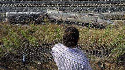 Un habitant d'Angrois regarde le train sorti de la voie, vendredi 26 juillet 2013, apr&egrave;s la catastrophe ferroviaire de Saint-Jacques-de-Compostelle, en Espagne. (MIGUEL RIOPA / AFP)