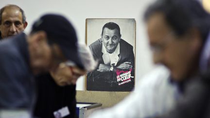 Des b&eacute;n&eacute;ficiaires et b&eacute;n&eacute;voles des Restos du c&oelig;ur devant le portrait de Coluche, le 28 novembre 2011 &agrave; Villeurbanne (Rh&ocirc;ne).&nbsp; (JEAN-PHILIPPE KSIAZEK / AFP)