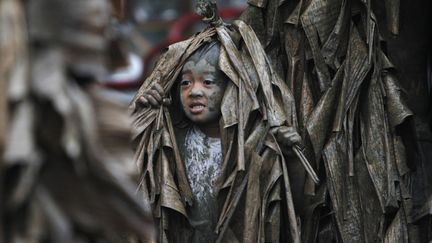 Une jeune gar&ccedil;on recouvert de boue et de feuilles de bananes r&eacute;clame des bougies &agrave; l'occasion de la traditionnelle f&ecirc;te de la saint-Jean &agrave; Manille (Philippines), le 24 juin 2013. (CHERYL RAVELO / REUTERS)