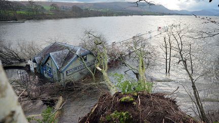 Des arbres sont tombés sur une&nbsp;rue submergée de Pooley Bridge (Angleterre) le 7 décembre 2015. La tempête Desmond a provoqué des inondations dans le nord de l'Angleterre. Certaines zones ont reçu en 24h l'équivalent d'un mois de précipitations. (PAUL ELLIS / AFP)