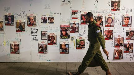 An Israeli soldier walks past portraits of hostages captured by the Islamist movement Hamas on November 16, 2023 in Tel Aviv (Israel).  (AHMAD GHARABLI / AFP)